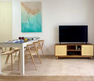 ein Wohnzimmer mit Tisch und Fernseher in der Unterkunft Canaryislandshost l Coral in Puerto del Carmen