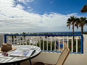 einen Tisch und Stühle auf einem Balkon mit Blick auf den Strand in der Unterkunft Canaryislandshost l Coral in Puerto del Carmen