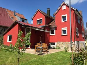 ein rotes Haus mit einem Tisch davor in der Unterkunft Vive-Là übernachten mit Charme! in Kusterdingen