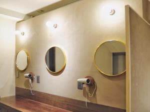 a bathroom with three mirrors on the wall at MATSUMOTO CASTLE hostel in Matsumoto