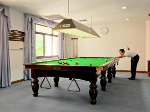 a man playing pool in a room with a pool table at Panorama Golf And Country Club in Ban Mai Samrong