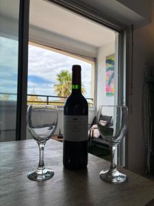 una bottiglia di vino e due bicchieri di vino su un tavolo di Evasion marine, appartement idéalement situé a Cap d'Agde