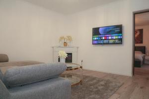 Una sala de estar con un sofá y un televisor en la pared. en Azur House2, en Cluj-Napoca
