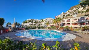 a swimming pool at a resort with palm trees and buildings at Sunny Playa del Cura in Playa del Cura