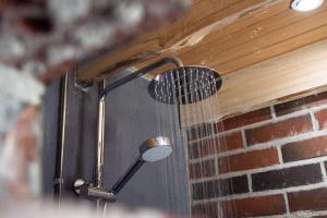 a shower with water coming out of a brick wall at Design Cabin with Jacuzzi, Sauna & Nature in Pertunmaa
