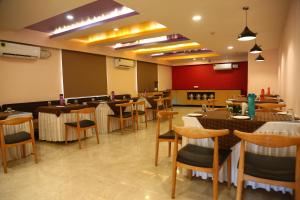 a restaurant with tables and chairs in a room at Hotel Konark Inn in Indore