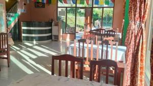 a dining room with a table and chairs and windows at Hotel Eco-Nest - Best Stay near Bhagsu Waterfall in McLeod Ganj