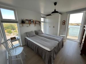 a bedroom with a bed and a chair and windows at Seaside House for 6 with Panoramic Ocean Views and Sauna near Gothenburg in Kärna +50 photos