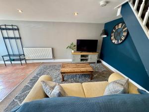 ein Wohnzimmer mit einer Couch und einer Uhr an der Wand in der Unterkunft Sunset Cottage in Hunstanton