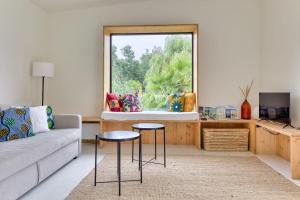 a living room with a couch and two stools in front of a window at Casa ZaO Jolie maison en bois brut de 50m2 à proximité des plages in Gouville-sur-Mer