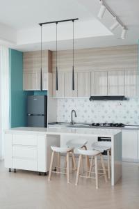 a kitchen with white cabinets and a sink and stools at Laurel Hill Suites CBD 2BR Apt, Spacious Balcony in Nairobi