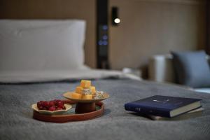een bord kaas en een boek op een bed bij Huazhu Luxurious Mountain Courtyard Private Hot Spring Resort in Longmen
