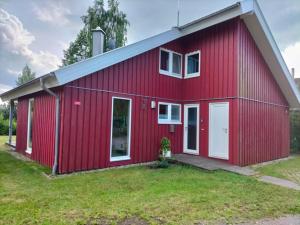 una casa roja con puertas blancas y un patio en Ferienhaus Büffel mit Sauna in Twist, en Neuringe 6 fotos más