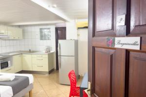 a small kitchen with a refrigerator and a red chair at Studio 2 - Bougainvillée - proche plage in Lazaret