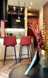 a table with two red chairs and a vase with flowers at 1 - Lisa Moderna - DonViore in Győr