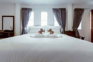 two dolls sitting on top of a white bed at Baansiwalin in Phra Nakhon Si Ayutthaya