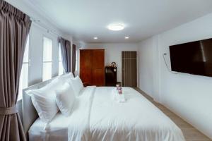 a bedroom with a white bed with a flat screen tv at Baansiwalin in Phra Nakhon Si Ayutthaya