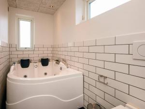 a white tub in a bathroom with white tiles at Exclusive Golf View Retreat in Rømø Kirkeby