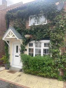 ein Backsteinhaus mit weißer Tür und Efeu in der Unterkunft Cosy Cottage Central Bawtry - 2 Bedroom - High End Furnishings in Bawtry