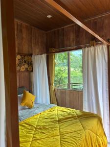 a bedroom with a bed with a yellow blanket and a window at Cure Monastery Family Resort in Marayoor