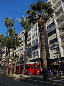a red train in front of a building with palm trees at Sea View Flat in Kaleici Old Town Near Sea Park in Antalya