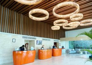 a lobby with orange counters and chandeliers at HARRIS Hotel Kuta Galleria - Bali in Kuta