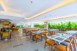 a restaurant with tables and chairs and windows at HARRIS Hotel Kuta Galleria - Bali in Kuta