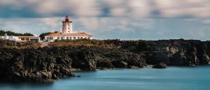 a lighthouse sitting on top of a rocky island at Casa da Baía da Manhenha in Manhenha