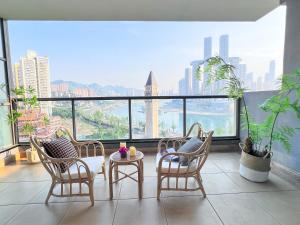 a balcony with chairs and a table and a view of the city at Chongqing Yifang B&B in Nan'an