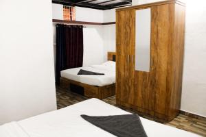 a bedroom with two beds and a wooden cabinet at The Aurora Coorg in Madikeri