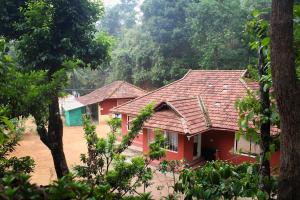 a red house with a red roof in a forest at The Aurora Coorg in Madikeri