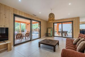 a living room with a couch and a tv and a table at Villa 10 pers à Carreyre, piscine chauffée, clim in Lacanau