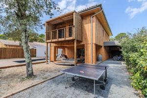 a house with a ping pong table in front of it at Villa 10 pers à Carreyre, piscine chauffée, clim in Lacanau