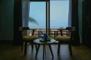 a table and chairs with a view of the ocean at Shivani Sunset Bay Beach Resort in Māvalli