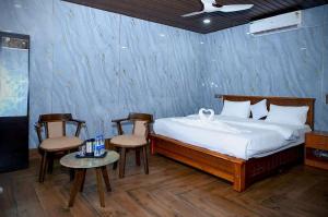 a bedroom with a bed with two chairs and a table at Shivani Sunset Bay Beach Resort in Māvalli +60 photos