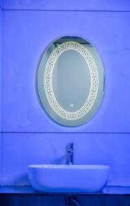 a mirror on a wall above a white sink at Shivani Sunset Bay Beach Resort in Māvalli