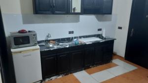 eine Küche mit schwarzen Schränken und einer Mikrowelle in der Unterkunft La gare agdal in Rabat