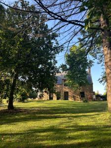 an old stone house with trees in the foreground at Songe de Clarté in Plouigneau