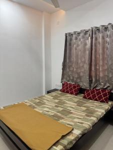 a bedroom with a bed with a bedspread and red pillows at Shri Mahalaxmi Excative yatri nivas in Kolhapur
