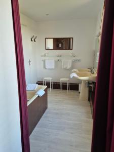 a bathroom with a tub and a sink and a mirror at La Roche du Marais in Omonville-la-Petite