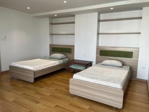 two beds in a room with wooden floors at Rosewood Sridaan in Ban Khlong Samrong