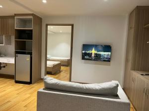 a living room with a couch and a television on a wall at Rosewood Sridaan in Ban Khlong Samrong