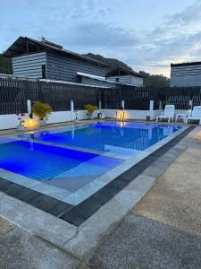a swimming pool with white chairs and a blue pool at The Star House in Patong Beach