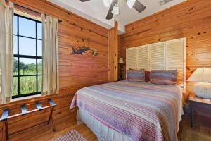 a bedroom with wooden walls and a bed with a window at Rustic Retreat in Ocean Springs