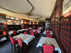 a restaurant with white tables and red chairs at LOGIS Hôtel & Restaurant - Les Arcades in Dieppe