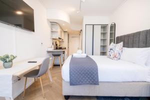 a bedroom with a bed and a desk and a kitchen at 1007 Zeeland - Top Floor Stylish Studio Near CTICC in Cape Town