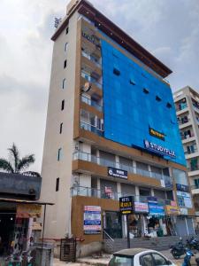 a tall building with a blue facade on a street at Hotel R Gold in Vadodara