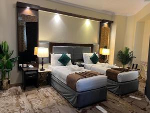 een hotelkamer met twee bedden en een bureau bij Sky View Hotel, Madinah in Al Madinah