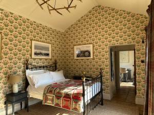 a bedroom with a bed in a room with wallpaper at The Gatehouse in Trimingham
