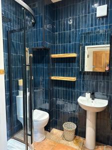 a blue tiled bathroom with a toilet and a sink at The Gatehouse in Trimingham